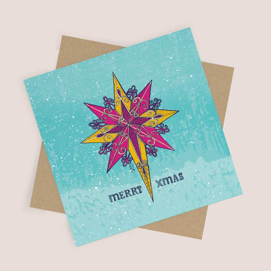 Christmas card featuring an intricate magenta and yellow star design against a snowy blue background with the text "Merry Xmas.