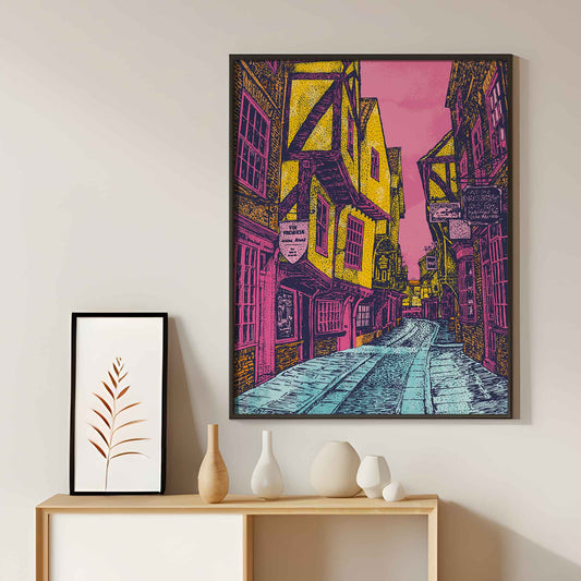 Vibrant art print of The Shambles, York, featuring colourful medieval buildings on a pink and yellow street scene.