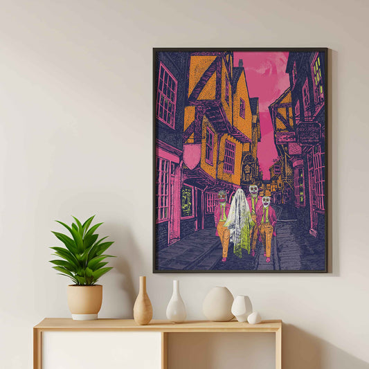 A colourful Halloween print featuring three figures in costumes walking down the historic Shambles in York. The print has detailed hand-drawn architecture and vivid colours.